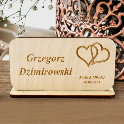 Rustykalna winietka na wesele z drewna z precyzyjnym grawerem imienia gościa oraz motywem serc od Studio MAYA.
