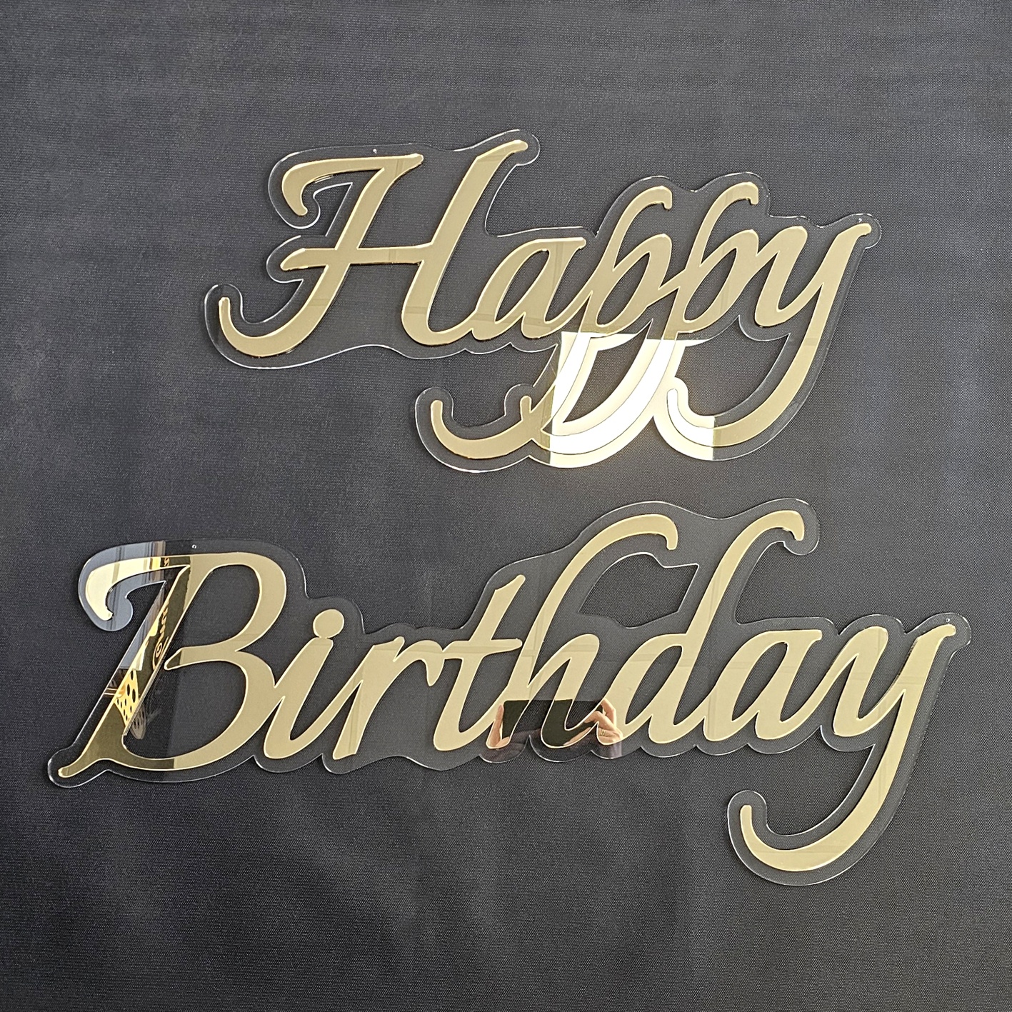Elegancki złoty napis urodzinowy Happy Birthday wykonany z lustrzanej plexi 3D na przezroczystym podkładzie.