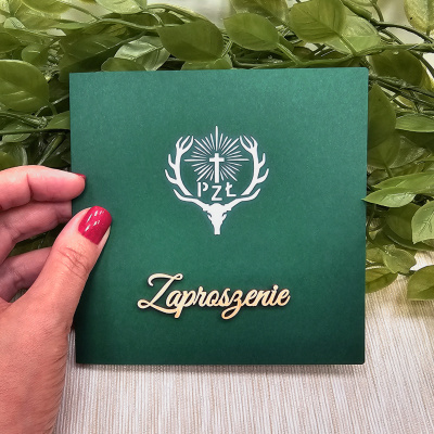Eleganckie zaproszenia myśliwskie z ciemnozieloną okładką, drewnianym napisem „Zaproszenie” i laserowo wycinanym logo Polskiego Związku Łowieckiego.