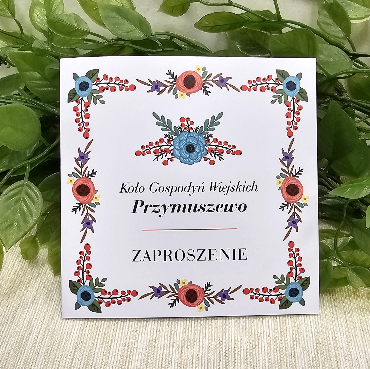 Eleganckie zaproszenia Koło Gospodyń Wiejskich w formacie 14 × 14 cm z kwiatową grafiką oraz nazwą miejscowości na okładce.
